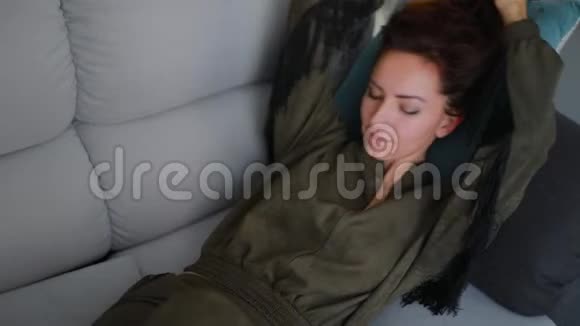 美丽的黑发女人躺在装饰枕头上休息视频的预览图