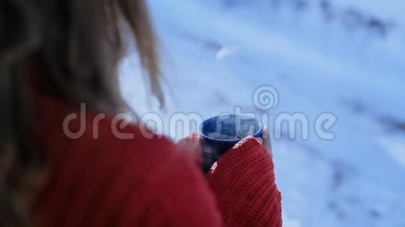 穿红色毛衣的女人在外面拿着蓝色咖啡杯视频的预览图