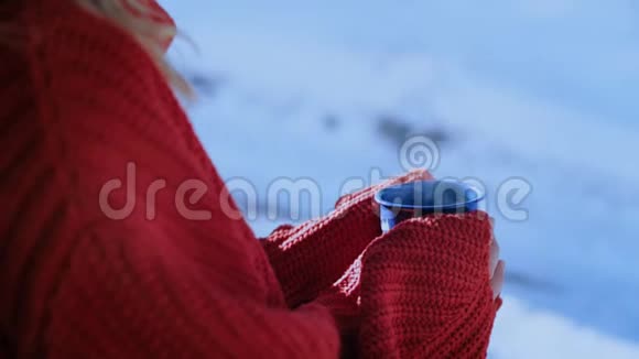 穿红色毛衣的女人在外面拿着蓝色咖啡杯视频的预览图