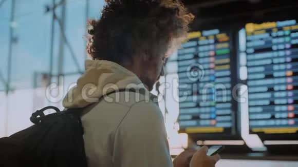 靠近机场信息屏幕的男性千禧旅行者视频的预览图