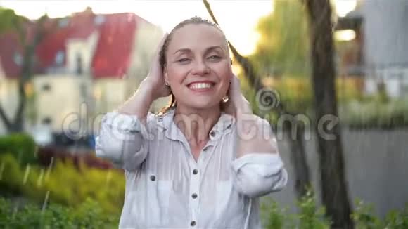 快乐的年轻微笑的女人在雨天有乐趣开朗的女士有湿发在夏季公园视频的预览图
