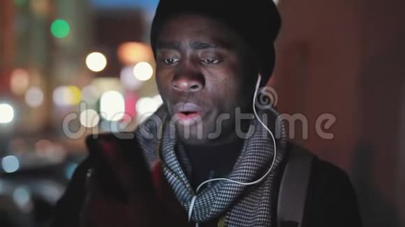 非洲男子夜间用耳机听音乐特写视频的预览图