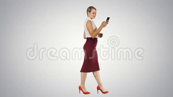美丽的年轻女子在智能手机上使用一个应用程序发送短信并在渐变背景下行走视频的预览图