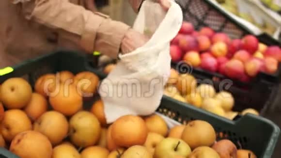 女人在超市买水果黄色漂亮的苹果她把袋子放在可重复使用的袋子里生态包装零视频的预览图