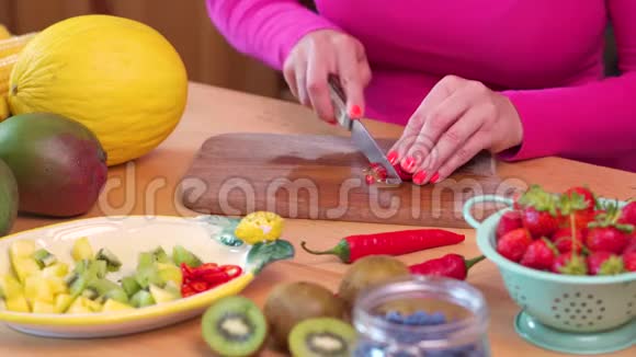 一个穿着粉色上衣的女人在桌子上切碎辣红辣椒视频的预览图