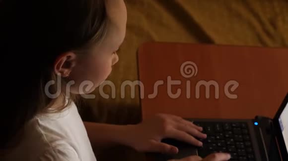 笔记本电脑上搜索引擎中的女孩打字查询孩子们晚上在房间里玩电脑年轻女孩在做家庭作业视频的预览图