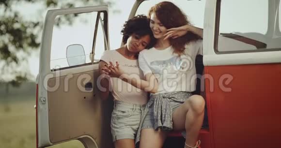 两个90年代的年轻女性有一个寒冷的外出坐在他们的复古巴士并有一个愉快的时间在一起4k视频的预览图