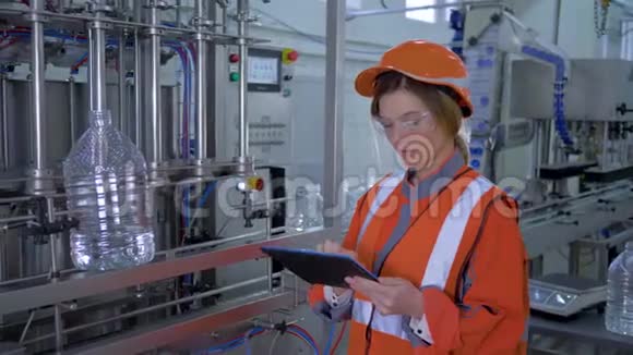 强大的女性在重工业微笑的工厂工人女孩进入头盔使用数字平板电脑检查和控制视频的预览图