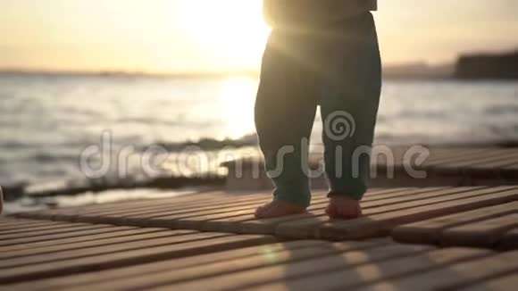 在海上日落时婴儿小腿踩在日光浴床上动作缓慢视频的预览图