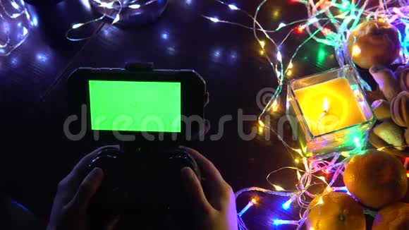 手动使用带有智能手机色度键绿色屏幕的游戏垫以蜡烛花环彩灯组成圣诞新年视频的预览图