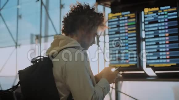 靠近机场信息屏幕的男性千禧旅行者视频的预览图