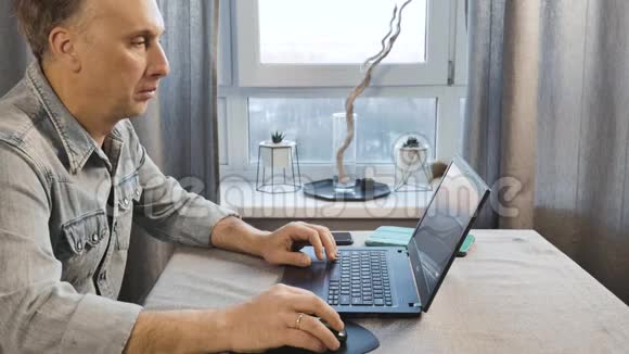 一个在笔记本电脑上工作的中年人自由职业者在家工作侧视图视频的预览图