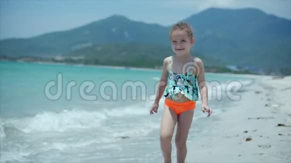 可爱的小男孩在沙滩上奔跑微笑着看着镜头库存录像视频的预览图