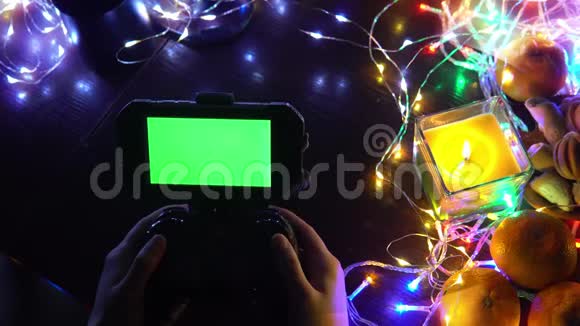 手动使用带有智能手机色度键绿色屏幕的游戏垫以蜡烛花环彩灯组成圣诞新年视频的预览图