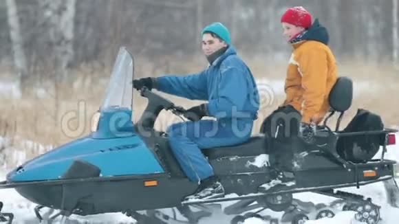冬天一个年轻人骑着雪车载着一个小男孩骑马视频的预览图