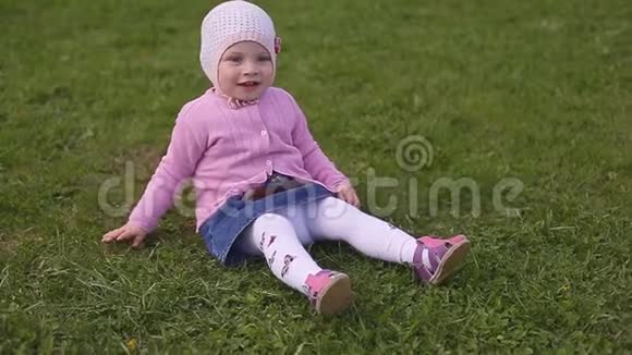 一个夏天戴着帽子的两岁小女孩坐在绿草上视频的预览图