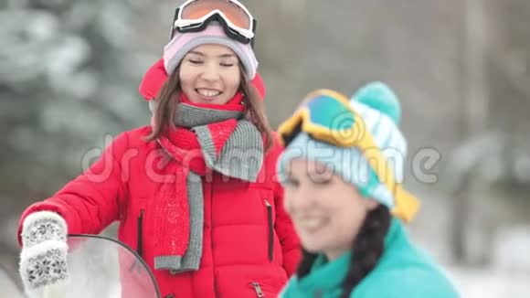冬天两个穿着五颜六色衣服的年轻女人在说话准备骑雪地摩托戴上眼镜视频的预览图