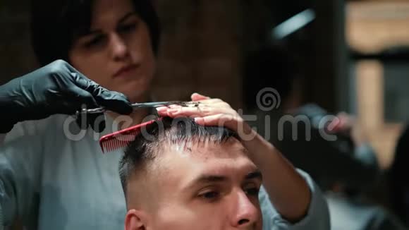 理发师用剪刀特写剪了客户的头发框架理发师梳头和理发视频的预览图