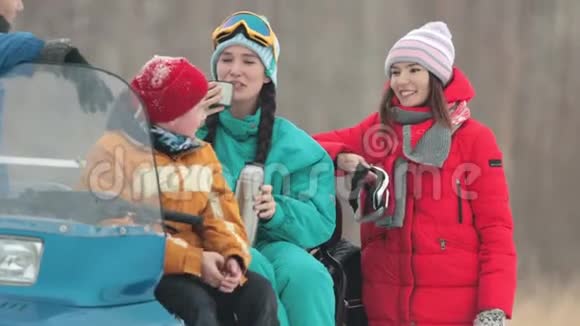冬天一家人穿着五颜六色的衣服坐在雪地上聊天喝着来自泰莫斯的热饮视频的预览图