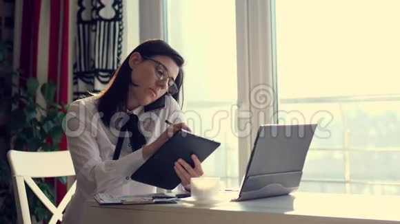 年轻的专注女性成功的女商人或带平板电脑和笔记本电脑的秘书看着屏幕打电话给视频的预览图