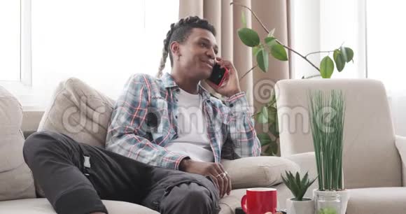 放松的男人在家里用手机说话视频的预览图