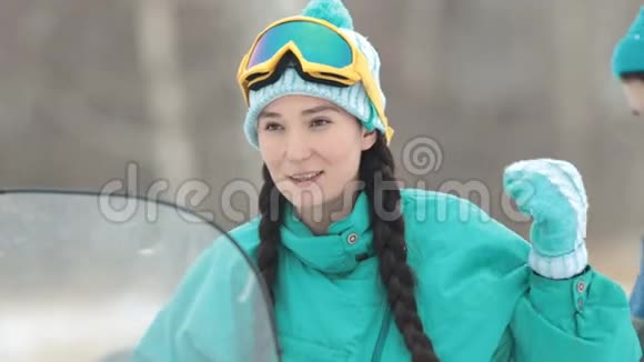 冬天一个穿着蓝色羽绒服的年轻女子坐在雪地摩托上说话视频的预览图