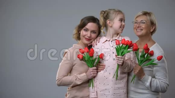 快乐的母亲女儿和奶奶抱着郁金香灰色背景春天的假期视频的预览图