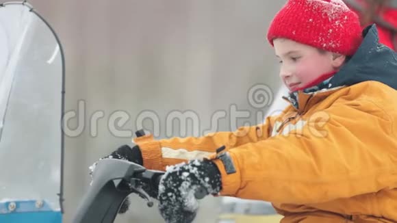 冬天一个兴奋的小男孩坐在雪地车上扭着气把视频的预览图