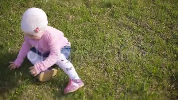 两岁的小女孩穿着针织帽在绿草上玩耍视频的预览图