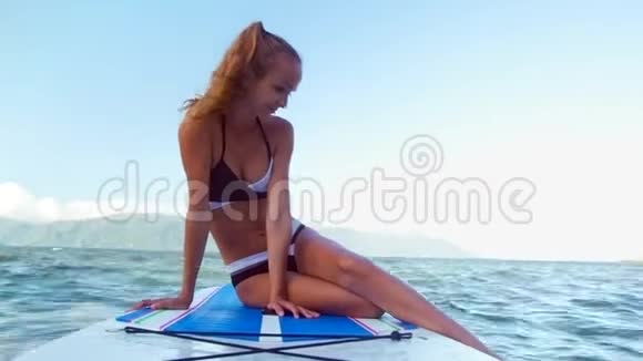 金发女孩把脚从桨板上放到水里视频的预览图