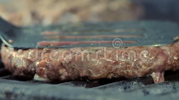 一个用铁铲压在烤架上的切块的特写侧视图被油炸并散发肉汁和毛刺视频的预览图