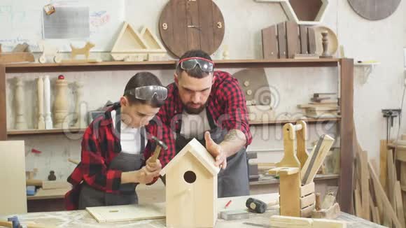 父亲和他的儿子一起在一个木作坊里工作建造一个鸟舍视频的预览图