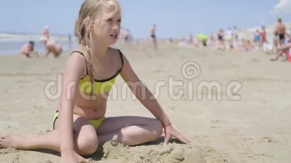 小女孩在海滩上玩沙子享受一个可爱的假期视频的预览图