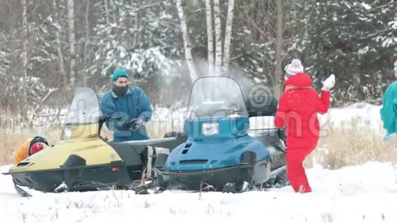 冬天一家人穿着五颜六色的羽绒服在雪地摩托中打雪球慢动作视频的预览图