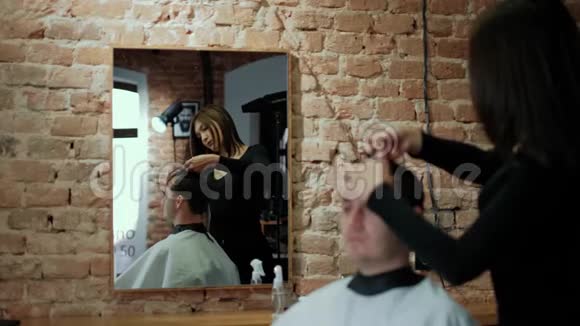 理发师用剪刀特写剪了客户的头发框架理发师梳头和理发视频的预览图