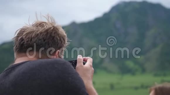 游客们在山上欣赏大自然年轻人给徒步旅行的女人拍照慢动作视频的预览图