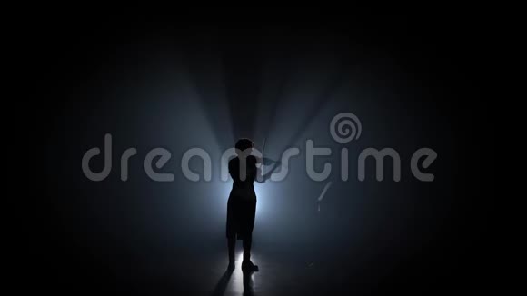 女人拉小提琴在黑暗中看着音乐台剪影黑烟背景视频的预览图