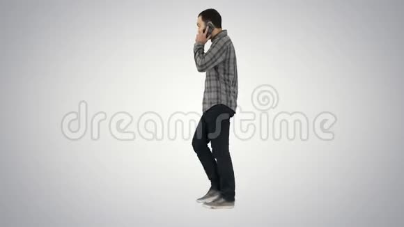 年轻的胡须男在梯度背景下的手机上行走和交谈视频的预览图