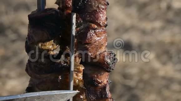 野餐时烤架上的新鲜猪肉用刀子从露天盘子里的烤肉串中取出视频的预览图