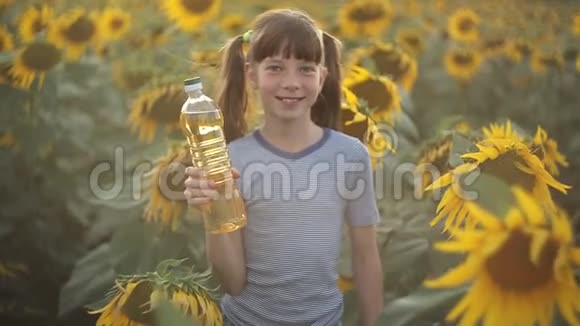 女孩拿着一瓶植物油站在田野里向日葵农业有机和健康食品视频的预览图