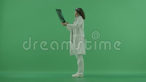 医生站在左边用肩膀握着电话在绿色屏幕上探索x光视频的预览图