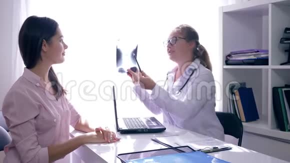 有好消息的医生手里拿着一张x光讲述了一位年轻女性在生育诊所的健康状况视频的预览图