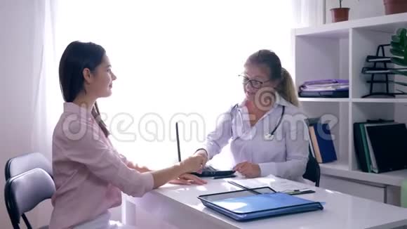 手里拿着x光的医生的好消息在生育诊所接待的幸福妇女病人视频的预览图