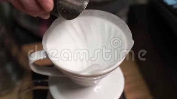 将新鲜磨碎的咖啡豆倒入带有纸过滤器的咖啡滴头上视频的预览图