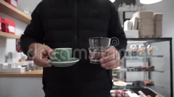 顾客把咖啡和一杯水的浓咖啡杯拿到桌上视频的预览图