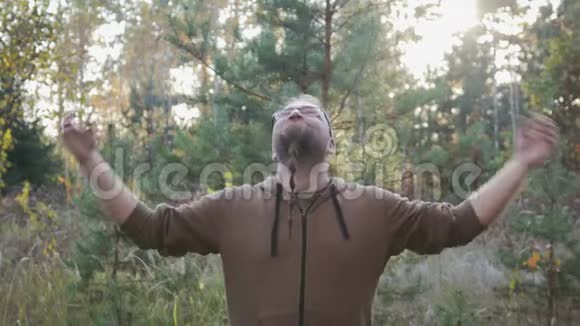 一个留着胡子的年轻人把手举到天空的肖像快乐和幸福的概念视频的预览图