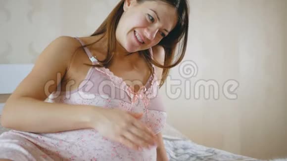 怀孕的女孩和一只猫休息一个女人抚摸她圆圆的肚子抚摸她的宠物床上的动物靠近视频的预览图