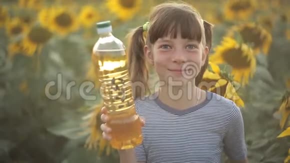 女孩拿着一瓶植物油站在田野里向日葵农业有机食品和健康食品视频的预览图