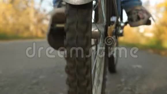 女孩推自行车踏板的腿车轮与踏车特写骑自行车在沥青路上视频的预览图