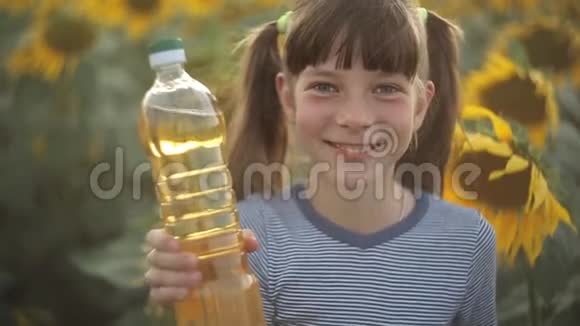 女孩拿着一瓶植物油站在田野里向日葵农业有机食品和健康食品视频的预览图